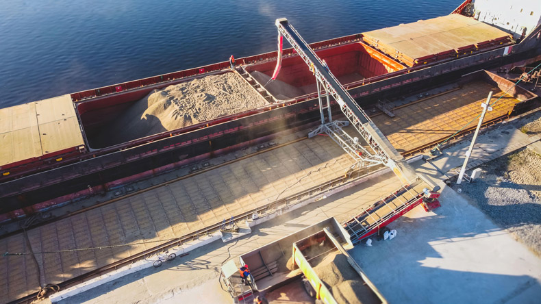 Комбайн в житно поле на фона на газови пламъци, графики за цени на торове и борсови котировки, символизиращи кризата на маржа в земеделието.